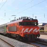 a red and green train is traveling down the tracks